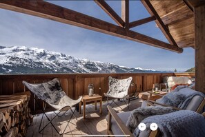 Relax on the deck with a view of snow-capped mountains, surrounded by a mix of modern and rustic furniture.