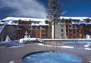 Relax by the pool at this resort, where guests can enjoy a swim in one of two pools, surrounded by a tree and a multi-story building.