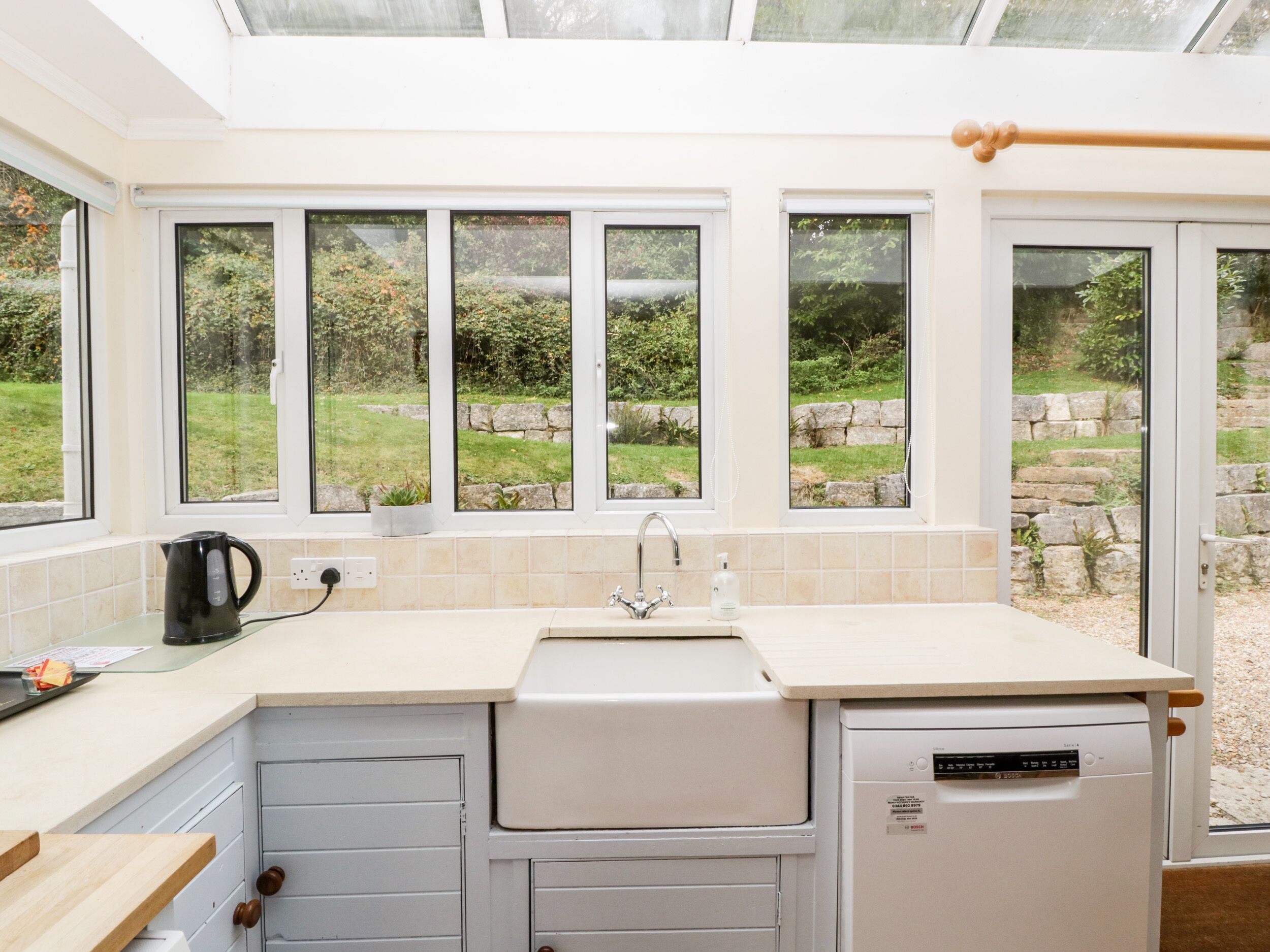 A kitchen with a dishwasher, a kettle, and a sink.