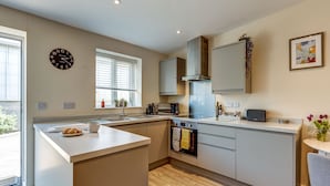 A modern kitchen with a central island, built-in oven, and a microwave.