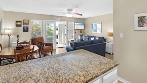 A spacious living area with a kitchen, dining table, and a ceiling fan. - Updated First Floor Condo, Close to Pool, Free Beach Service (Destin)