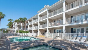 A multi-story hotel with a pool area, including a hot tub and lounge chairs. - Updated First Floor Condo, Close to Pool, Free Beach Service (Destin)