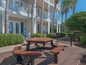 Enjoy a meal on the beachfront deck with a picnic table and benches, surrounded by lush greenery and palm trees.