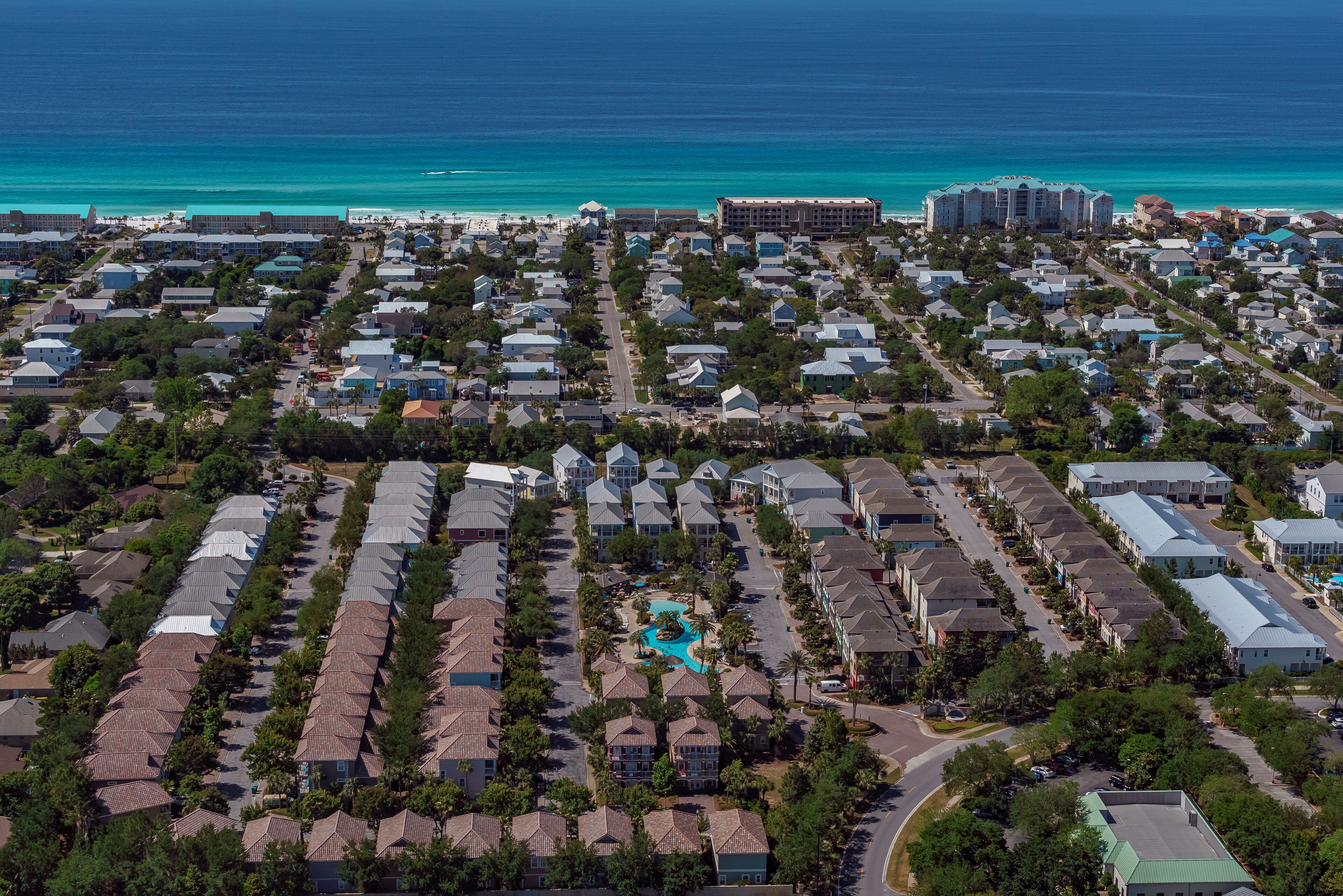 Zona residencial costera con edificios de varios pisos, una piscina central y acceso a la playa.