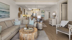 Un salon spacieux comprenant un grand canapé, une table basse et un coin repas avec des chaises et une table.