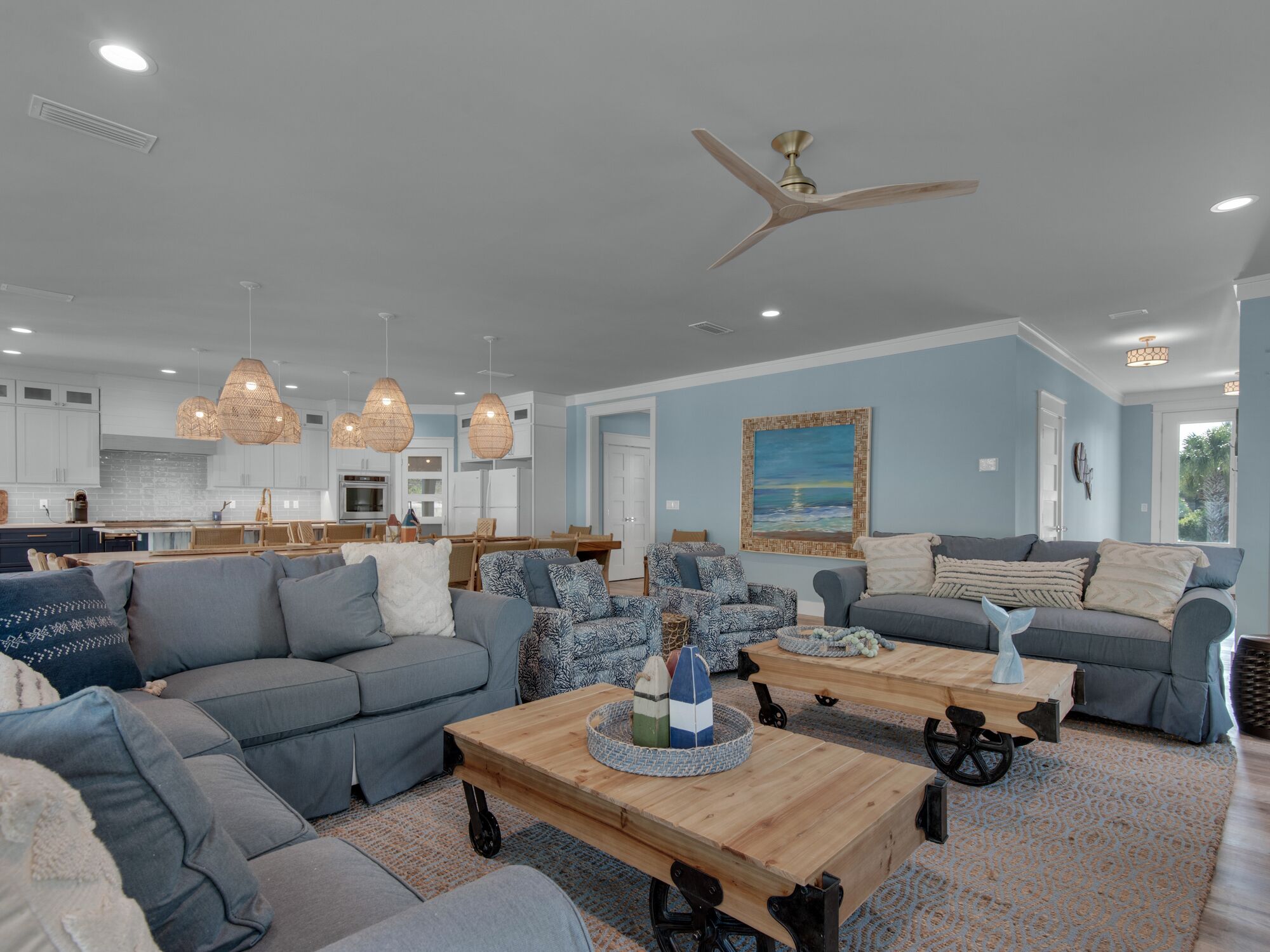 A spacious living area with a large gray sofa, a wooden coffee table, and a ceiling fan.