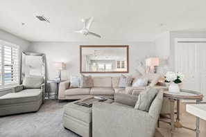 A modern living room with a sectional sofa, a small round table, and a ceiling fan. - Gulf Front, Gated Community (Destin)