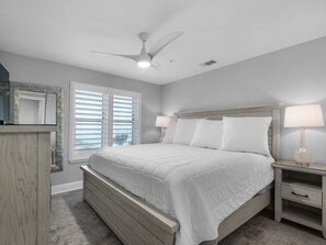 A bedroom with a bed, nightstands, a ceiling fan, and a window with blinds.