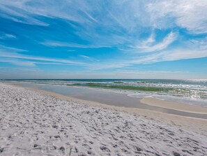 Ein Strand mit großem Sandbereich und sanften Wellen.