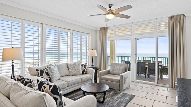 A spacious living room with a large window, a ceiling fan, and a view of the ocean. - Gulf Front * Endless Beach Views * Private Balcony * Pool, Hot Tub, Tennis (Destin)