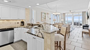A modern kitchen with white cabinets, a granite countertop, and a dishwasher. - Gulf Front * Endless Beach Views * Private Balcony * Pool, Hot Tub, Tennis (Destin)