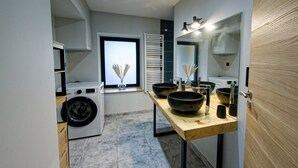 A modern bathroom with a washing machine, a large mirror, and a wooden vanity. - Cosy*SPA*Modern- at Ô JurassiK (Coteaux du Lizon)