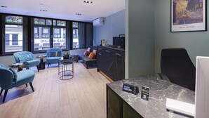 Une chambre d’hôtel moderne dotée d’un coin salon, d’un bureau avec un ordinateur et d’un tableau de Vincent van Gogh.