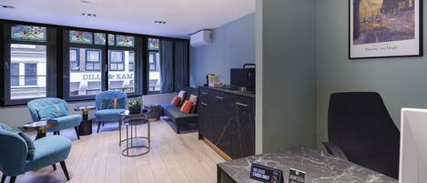 Una habitación de hotel moderna con zona de estar, un escritorio con computadora y un cuadro de Vincent van Gogh.
