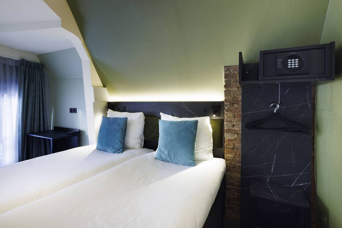 Habitación de hotel con una cama grande, dos almohadas, un televisor montado en la pared y una pared de mármol negro.