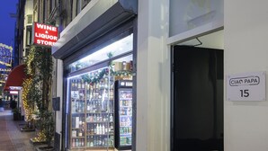 Une enseigne d’hôtel pour le CIAO HOTEL PAPA à Amsterdam, avec une devanture visible et une boutique de vins et de spiritueux située à côté.