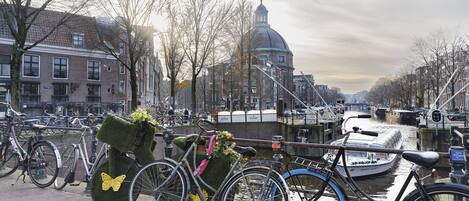 A canal with boats, bicycles, and a historic building with a dome.