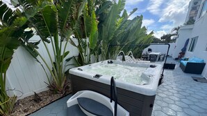 A hot tub with a step, surrounded by plants and a tiled patio. - 4/5 for 8, Steps to Beach-Jacuzzi, Furnished Patio (Hollywood)