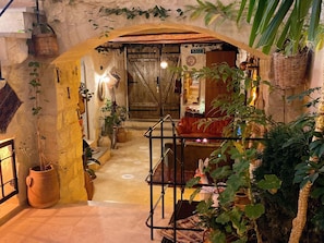 An interior with a rustic archway, a wooden door, and a seating area with cushions. - Shadow Cave House (Ürgüp)