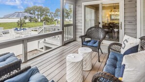 A covered outdoor area with wicker furniture, a white railing, and a view of the outdoors. - Enjoy Views of Calibogue Sound from Private Deck! (Hilton Head Island)