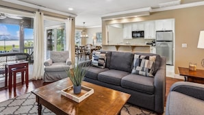 A modern living room with a grey sofa, wooden coffee table, and a dining area with a table and chairs. - Enjoy Views of Calibogue Sound from Private Deck! (Hilton Head Island)