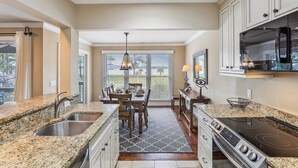A kitchen with granite countertops, stainless steel appliances, and a dining area with a view. - Enjoy Views of Calibogue Sound from Private Deck! (Hilton Head Island)