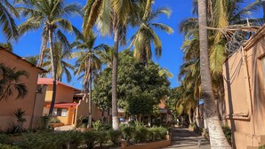 A narrow street lined with palm trees and buildings with red roofs. - Hotel Oasis (Mazatlán)