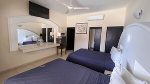 A hotel room with two beds, a ceiling fan, a flat-screen TV, a microwave, and a small table. - Hotel Oasis (Mazatlán)
