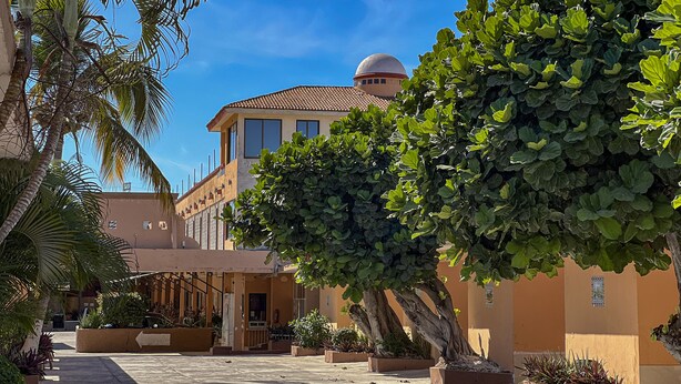 A building with a dome, palm trees, and a tiled roof. - Hotel Oasis (Mazatlán)