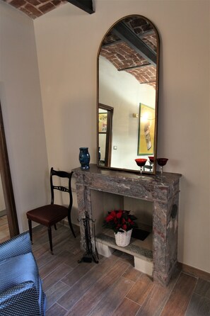 A room with a stone fireplace, a chair, a bench, and a large mirror.