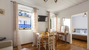 Una habitación acogedora con una mesa de comedor de madera, sillas, una pequeña cocina, una cama y un balcón con vistas.