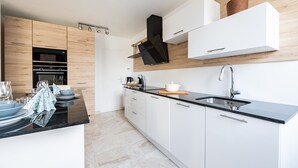 A modern kitchen with a black countertop, white cabinets, a built-in oven, and a stainless steel sink.
