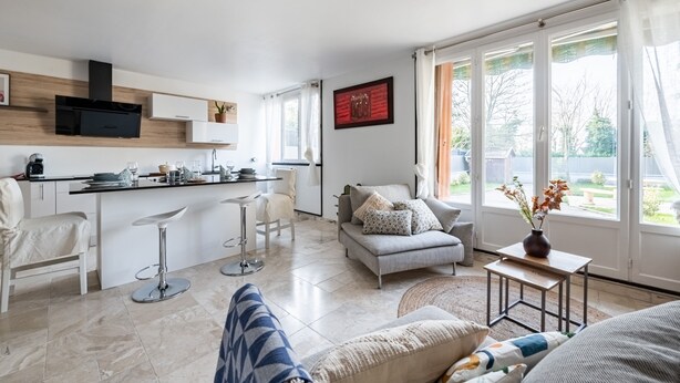 A modern living room with a sofa, a coffee table, and a dining area with a kitchen counter.