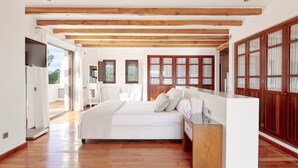 Un dormitorio amplio con una cama grande, vigas de madera en el techo y vistas al exterior.