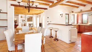 Una cocina amplia con vigas de madera, un área de comedor con mesa de vidrio y una silla roja de acento.