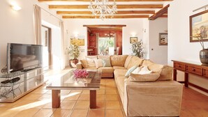 Una sala de estar con sofá, televisor y una mesa de centro de vidrio.