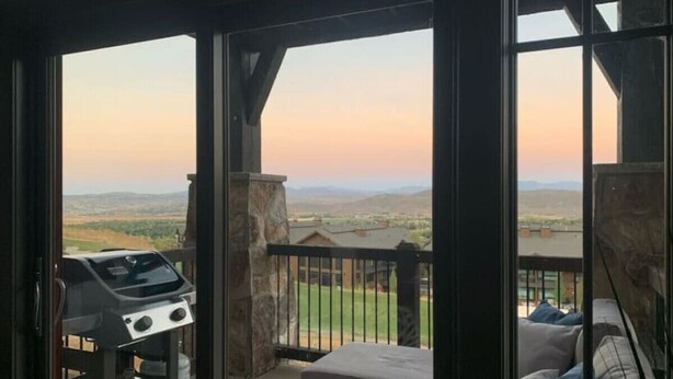 Un balcón con vistas a un paisaje, una parrilla y un sofá.