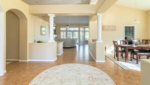 A spacious living area with a central island, a dining area with a wooden table and chairs, and a kitchen in the background. - Gardenesque oasis getaway w/cooling water misters (Phoenix)