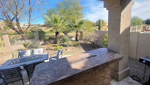 A patio area with a stone bar, seating, and a view of a landscaped garden. - Gardenesque oasis getaway w/cooling water misters (Phoenix)