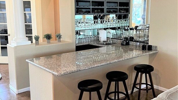A kitchen with a central island, bar stools, and a wine rack. - Gardenesque oasis getaway w/cooling water misters (Phoenix)