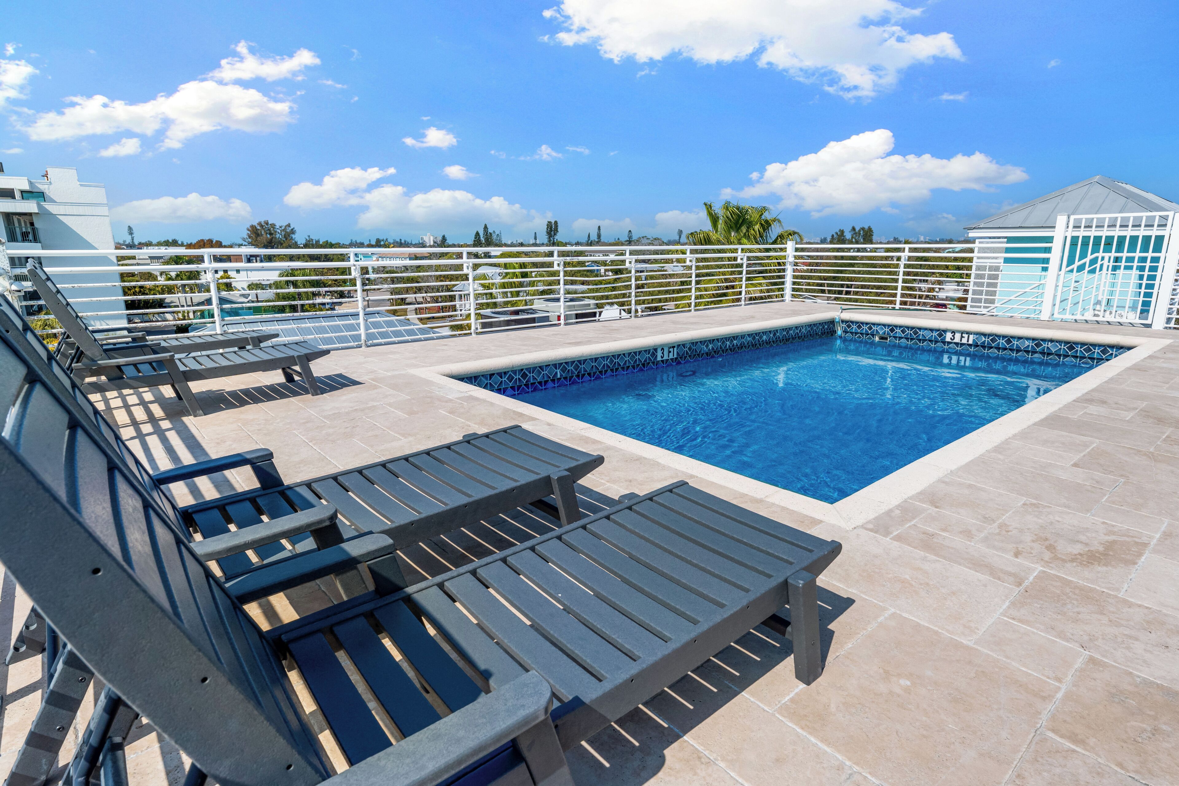 A rooftop pool area with lounge chairs and a small building.