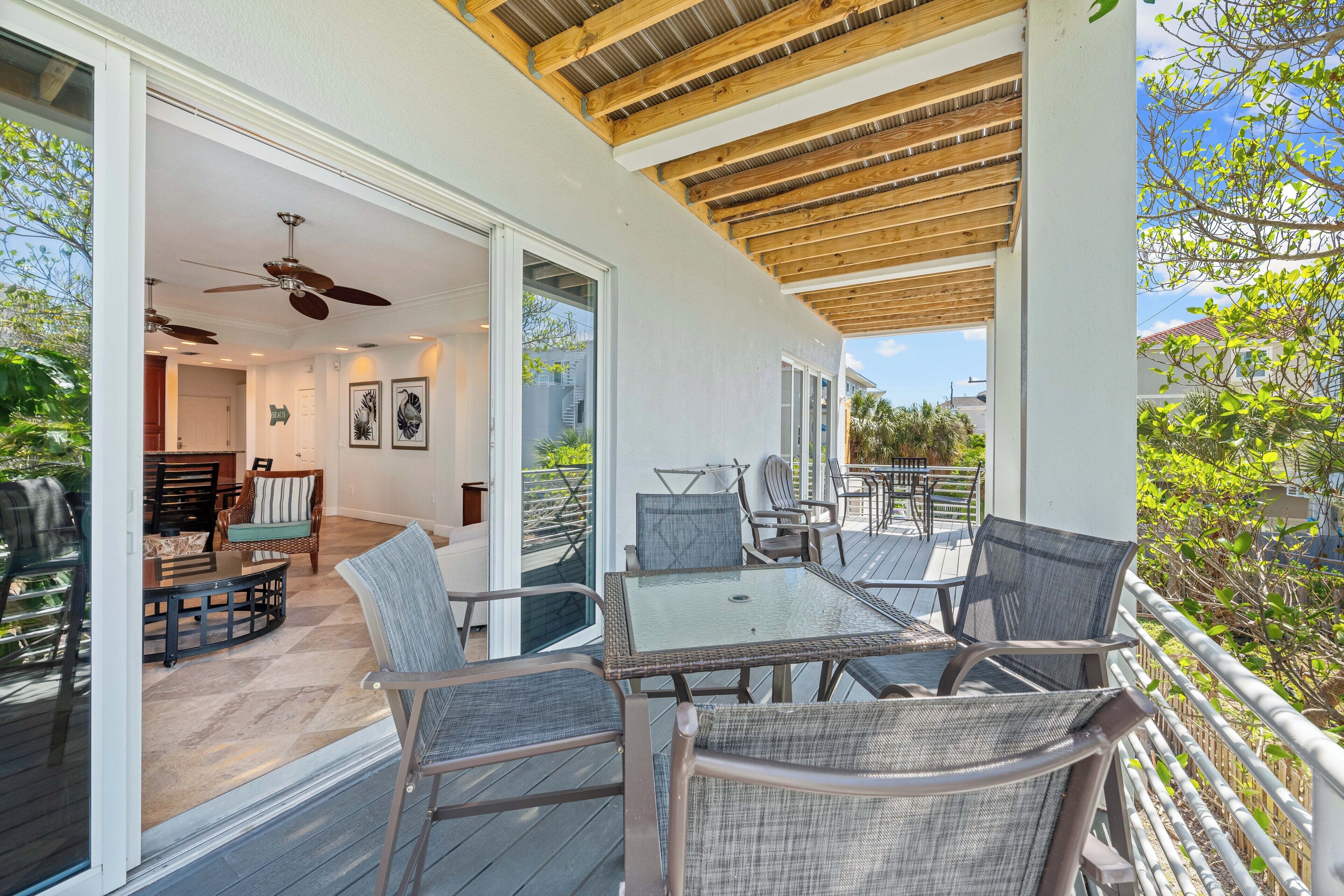 An outdoor patio with a table and chairs, a ceiling fan, and a view of the surrounding area.