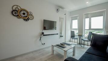 Una sala moderna con televisor de pantalla plana, una mesa de centro, un sofá y un adorno en la pared.