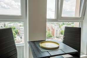 Una habitació amb una taula i dues cadires, una finestra amb vista a edificis, i una safata sobre la taula.