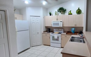 Functional kitchen with a refrigerator, microwave, oven, sink, and coffee maker, plus ample storage and a clean design.