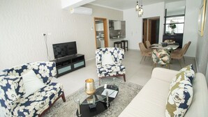 Una sala de estar con un sofá, sillones, una mesa de centro y un televisor.