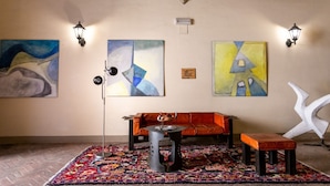 Una habitación con un sofá, dos mesas y pinturas abstractas en la pared.