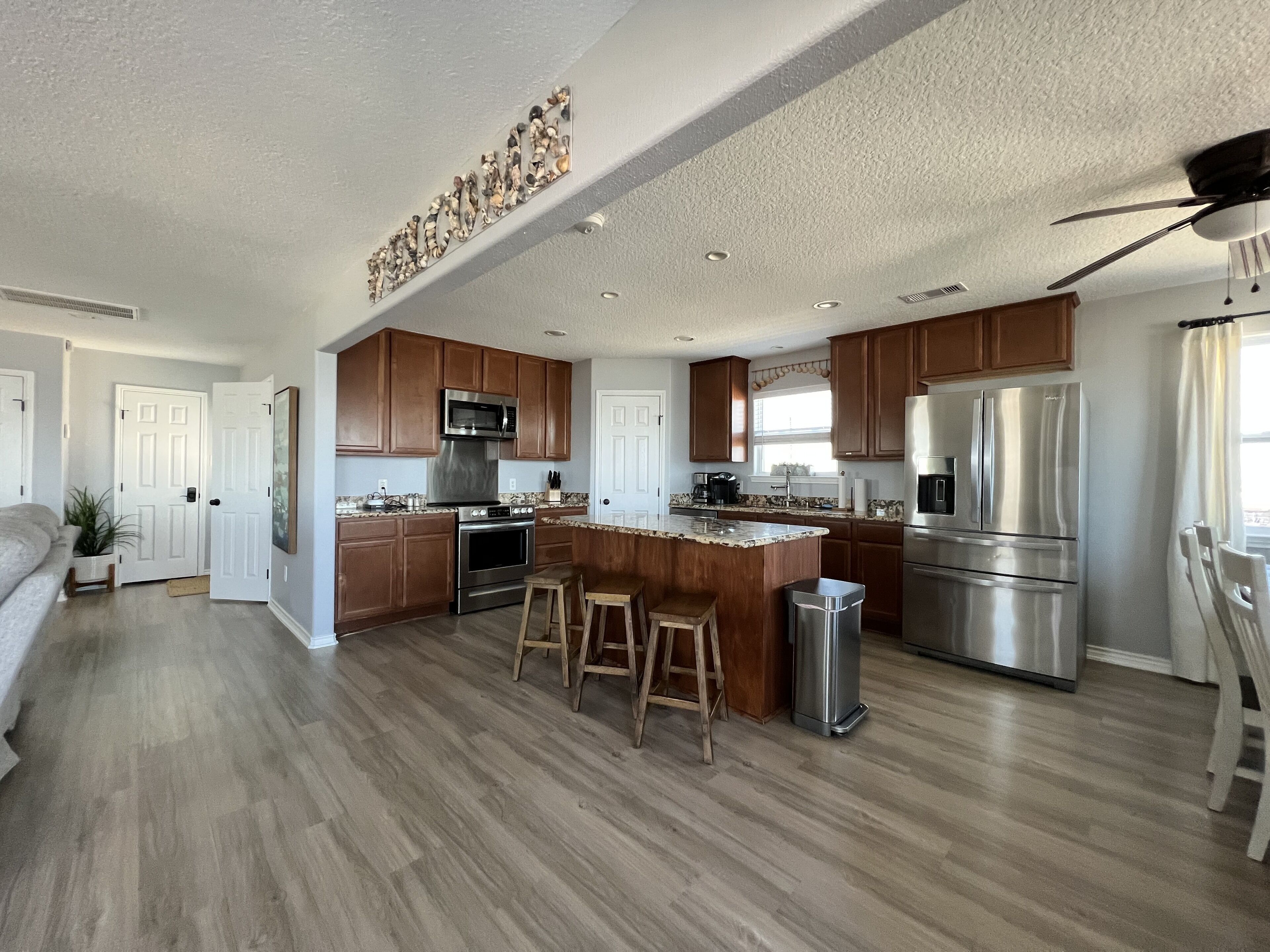 Una cocina moderna con armarios de madera, electrodomésticos de acero inoxidable y una isla central con taburetes.