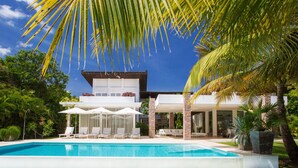 A modern house with a pool, surrounded by lush greenery and palm trees. - Luxury villa at Puntacana Resort & Club (Punta Cana)
