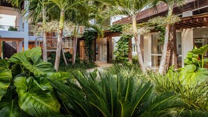 A modern house with a lush garden, featuring tall palm trees and large green plants. - Luxury villa at Puntacana Resort & Club (Punta Cana)